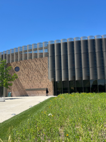 Modern building with textured brick and curved metal screen facade.