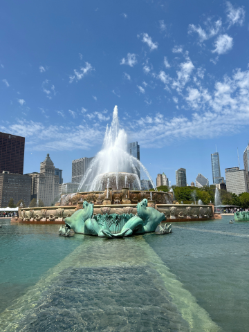 Buckingham Fountain in Chicago sprays water high into the air under a bright blue, slightly cloudy sky.