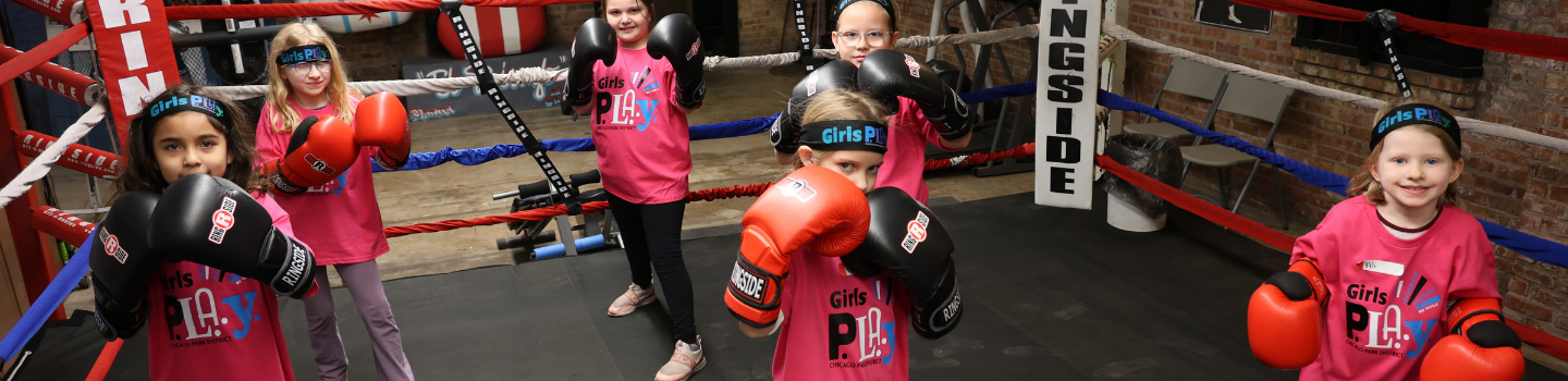 Boxing Gyms.png Five girls wearing boxing gloves stand in a boxing ring.