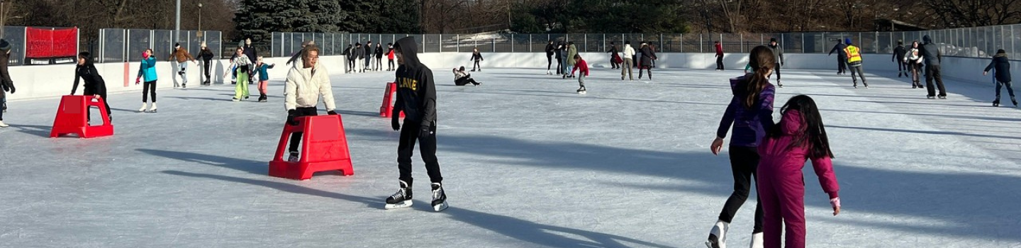Ice Rinks.png People ice skating at an outdoor rink. Some use red skating aids.
