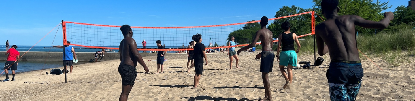Volleyball Courts (Outdoor).png People play beach volleyball on a sunny day.