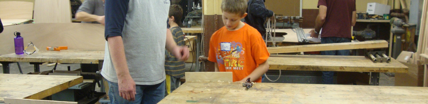 Woodshops.png Children and adults working with wood in a workshop.