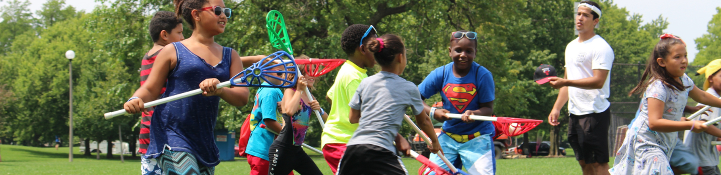 Children playing lacrosse in a park.