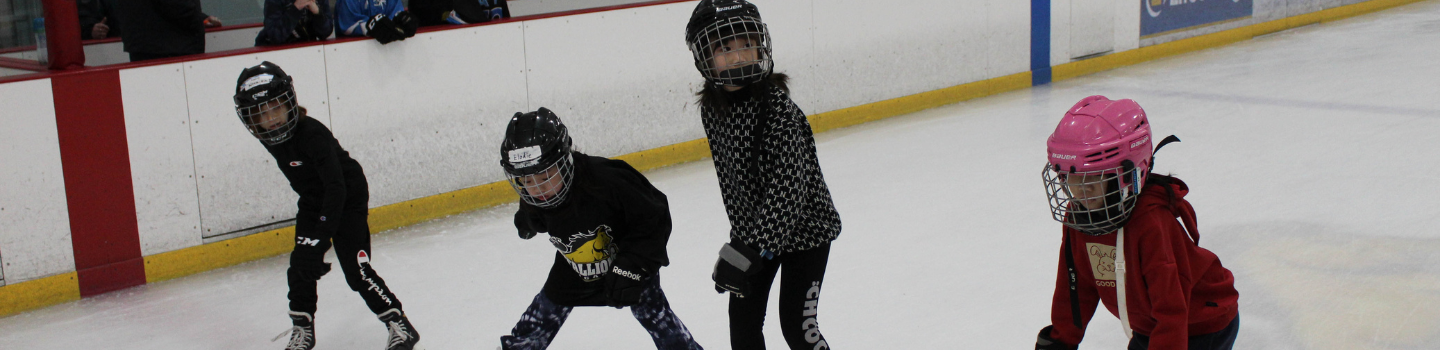 Four children learning to ice skate.