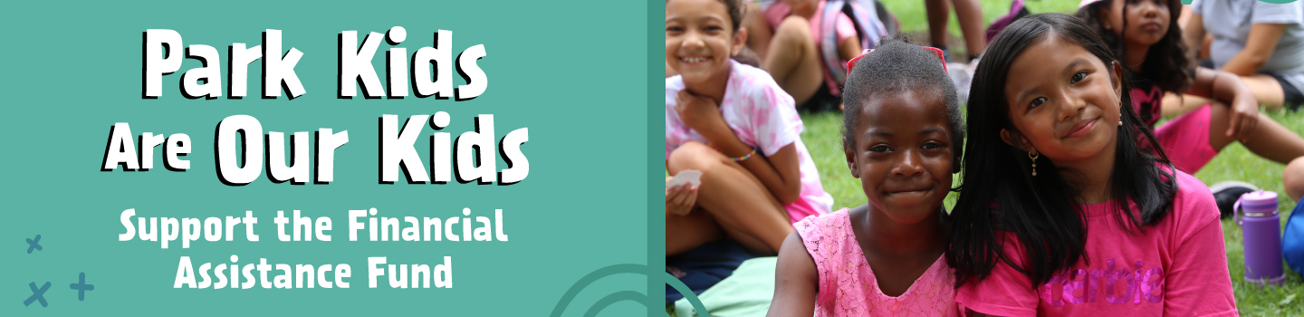 Two girls smile at the camera with other children in the background.