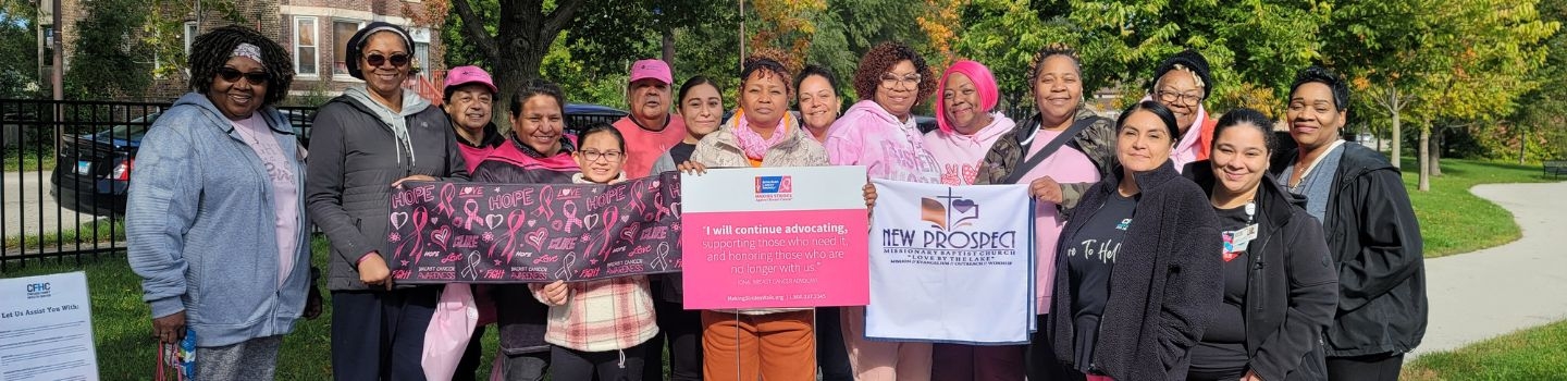 Group photo of people holding breast cancer awareness signs and a banner.