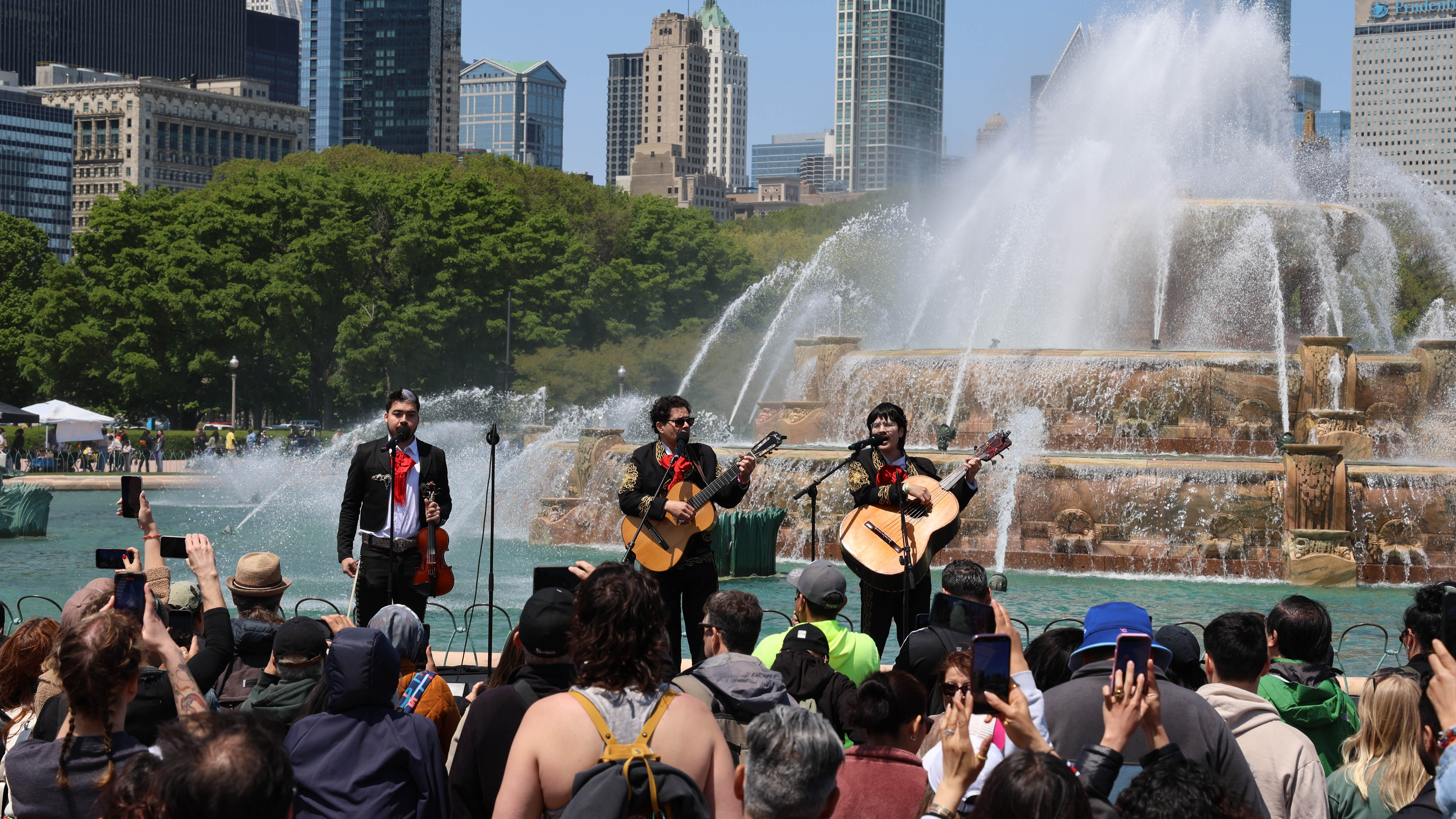 Mariachi band plays in front of Buckingham Fountain, Chicago. Crowd watches and takes photos.
