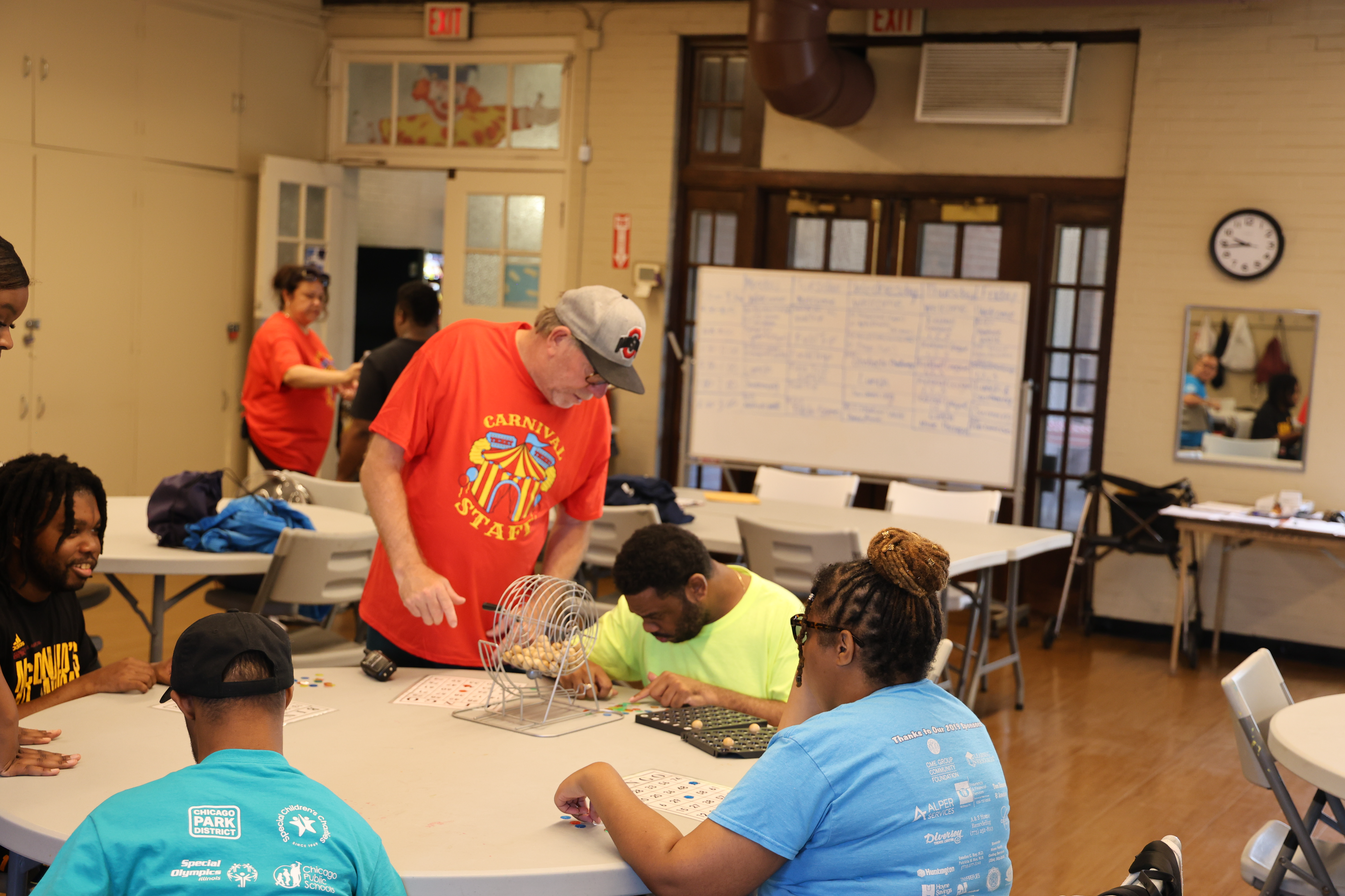 People play bingo at a table with a carnival staff member.
