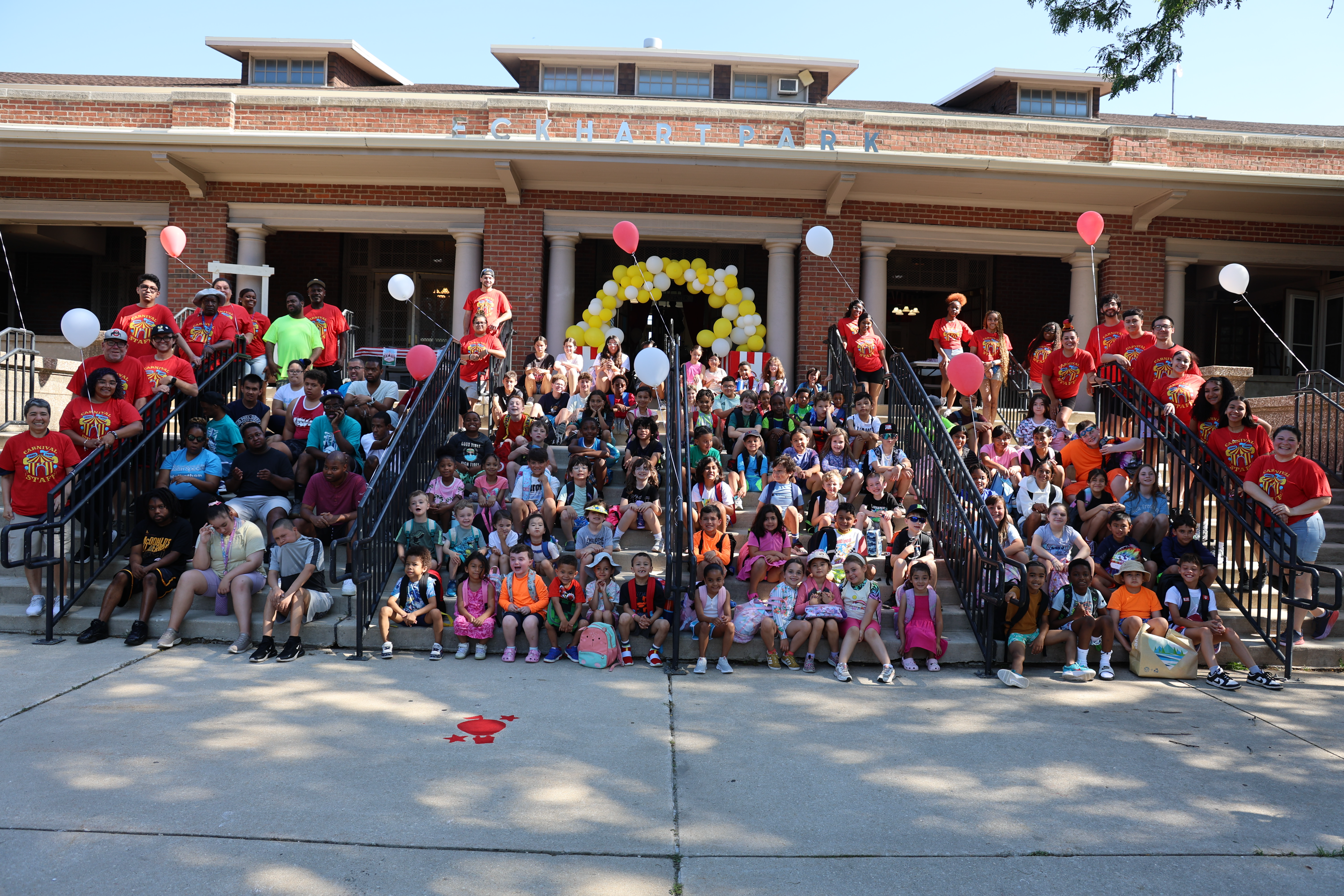 Large group of children and adults pose on steps of Eckhart Park building.
