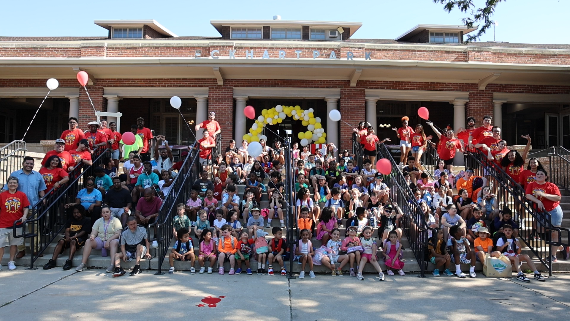 Large group of children and adults pose on steps of Eckhart Park building.