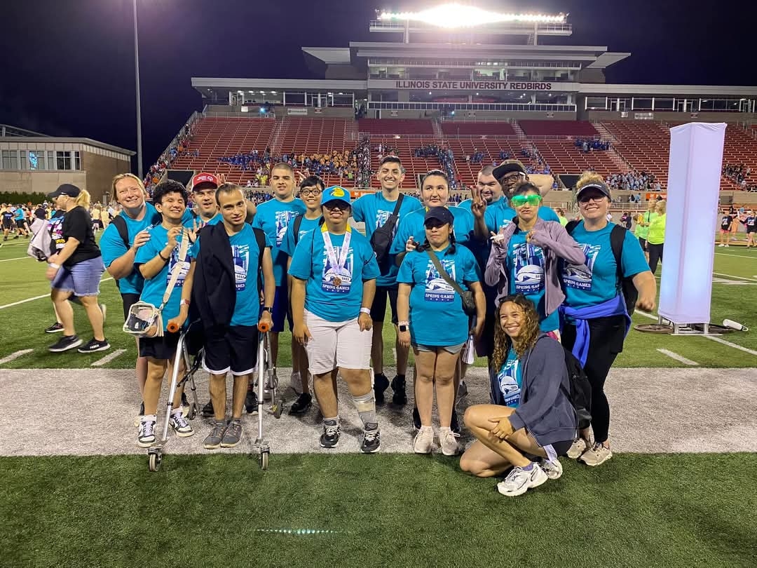 Group photo of Special Olympics athletes and coaches on a football field.