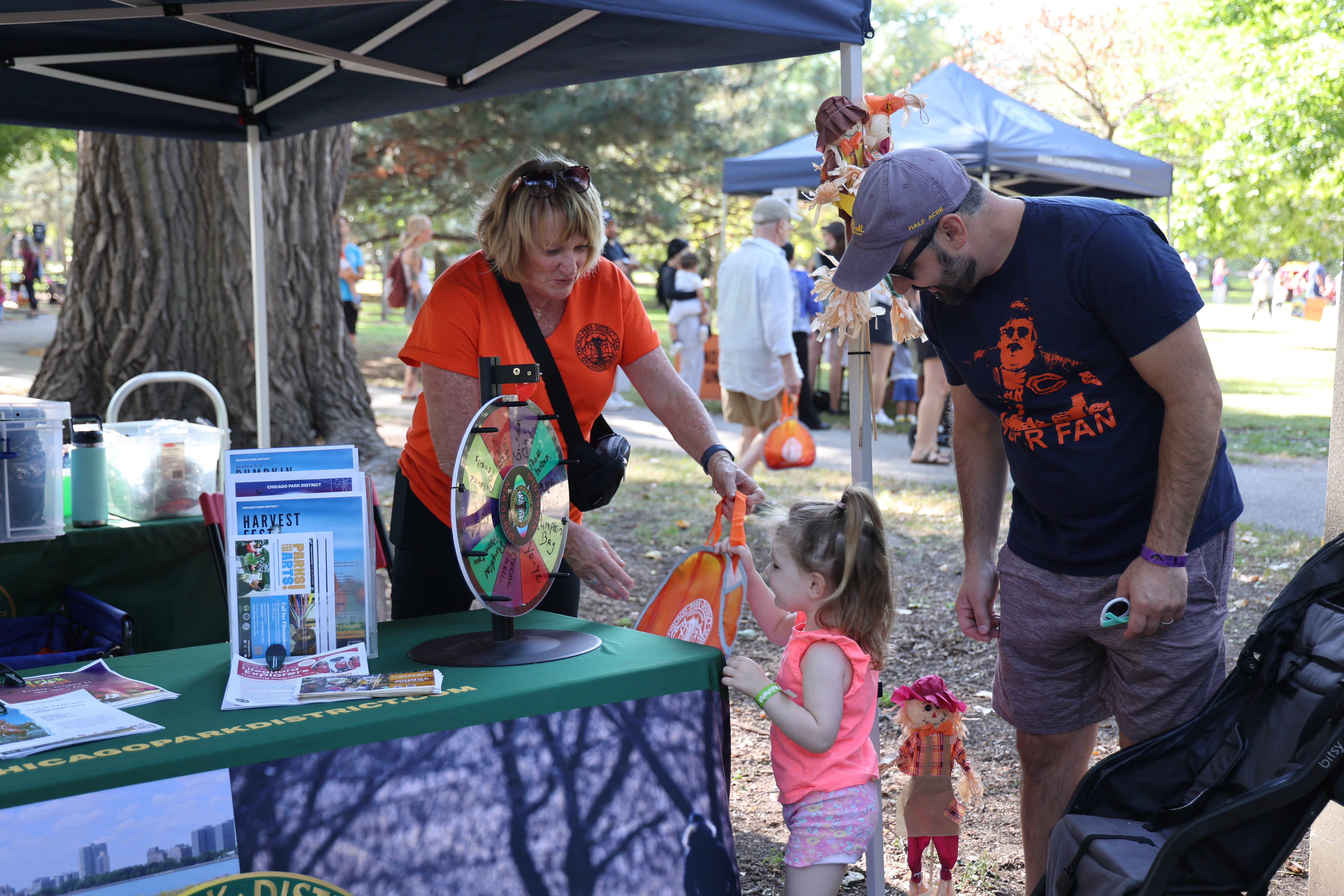 Photo of a woman assisting a child at a park district booth.