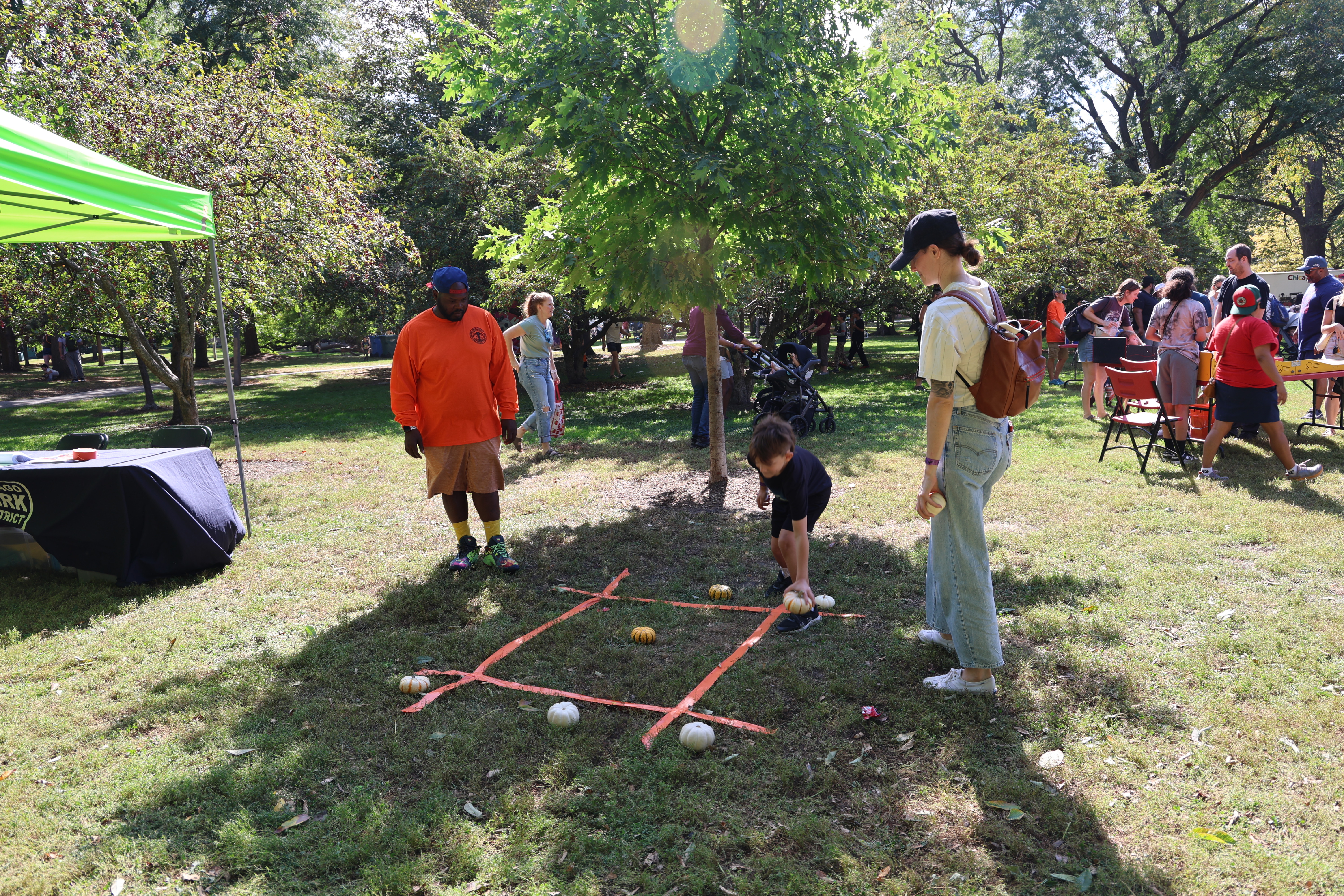 Outdoor photograph of kids playing tic-tac-toe with pumpkins.