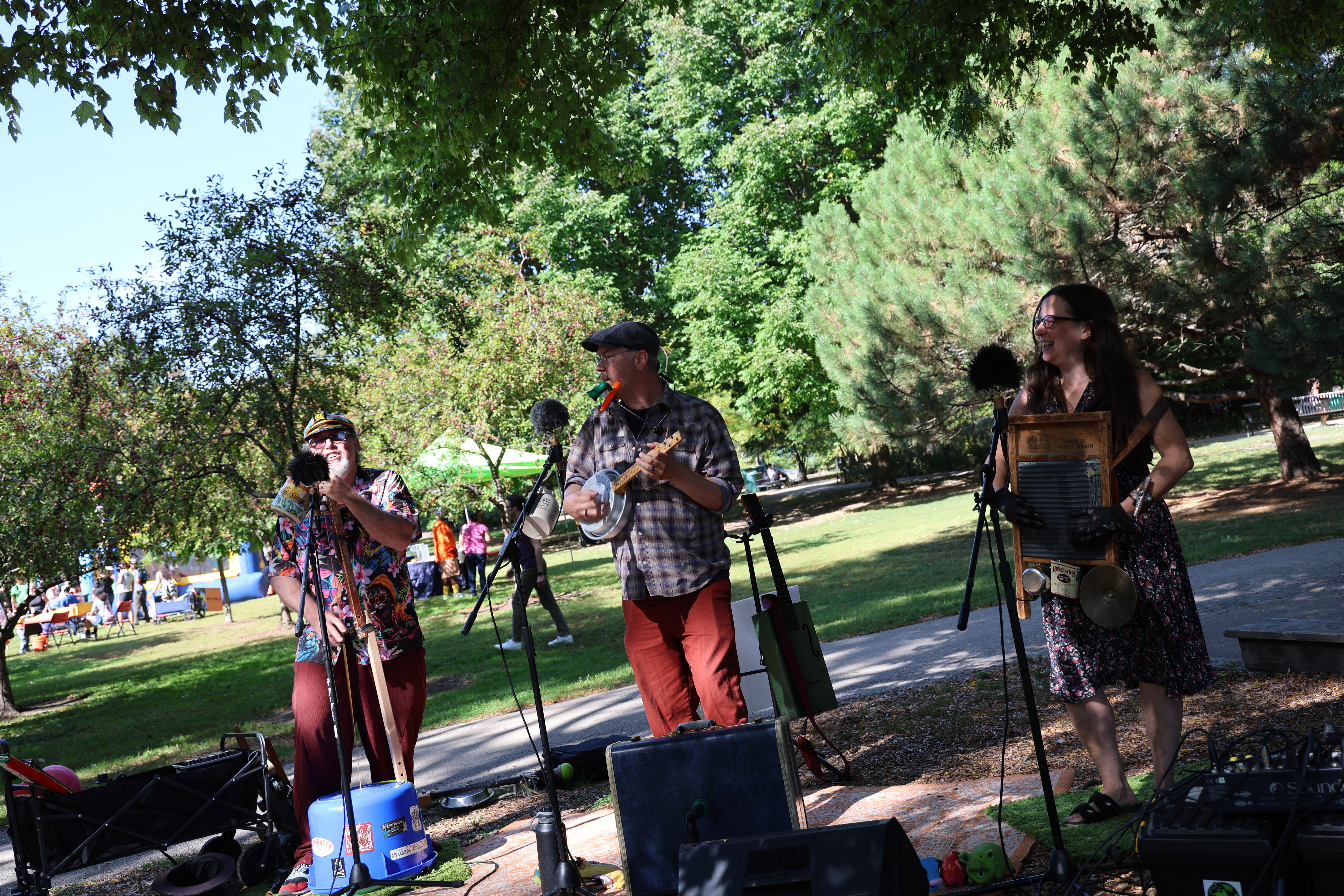 Outdoor photo of three musicians performing in a park.