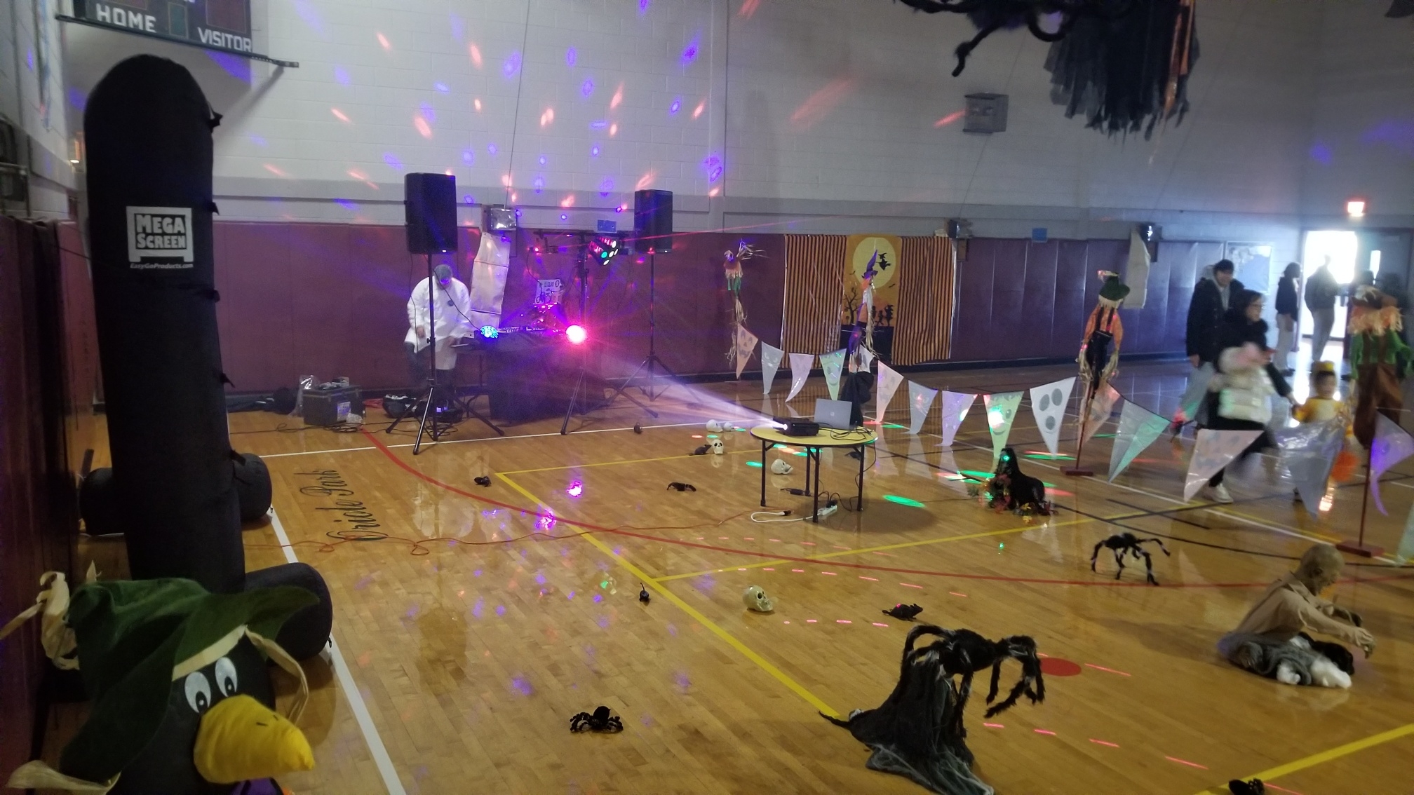 Photograph of a school gym decorated for Halloween, with a DJ setup and disco lights.