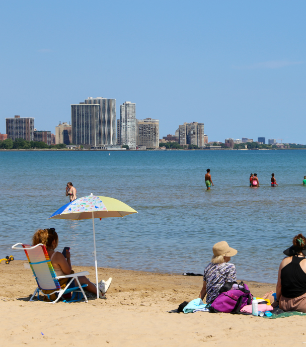 People relax on a sandy beach with the Chicago skyline in the background.