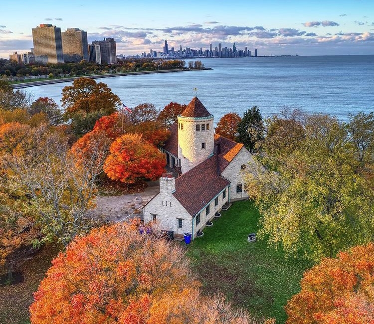 Aerial view of a historic building nestled among colorful autumn trees on the Chicago lakefront.