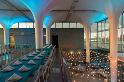 Modern event space with teal table settings and string lights.