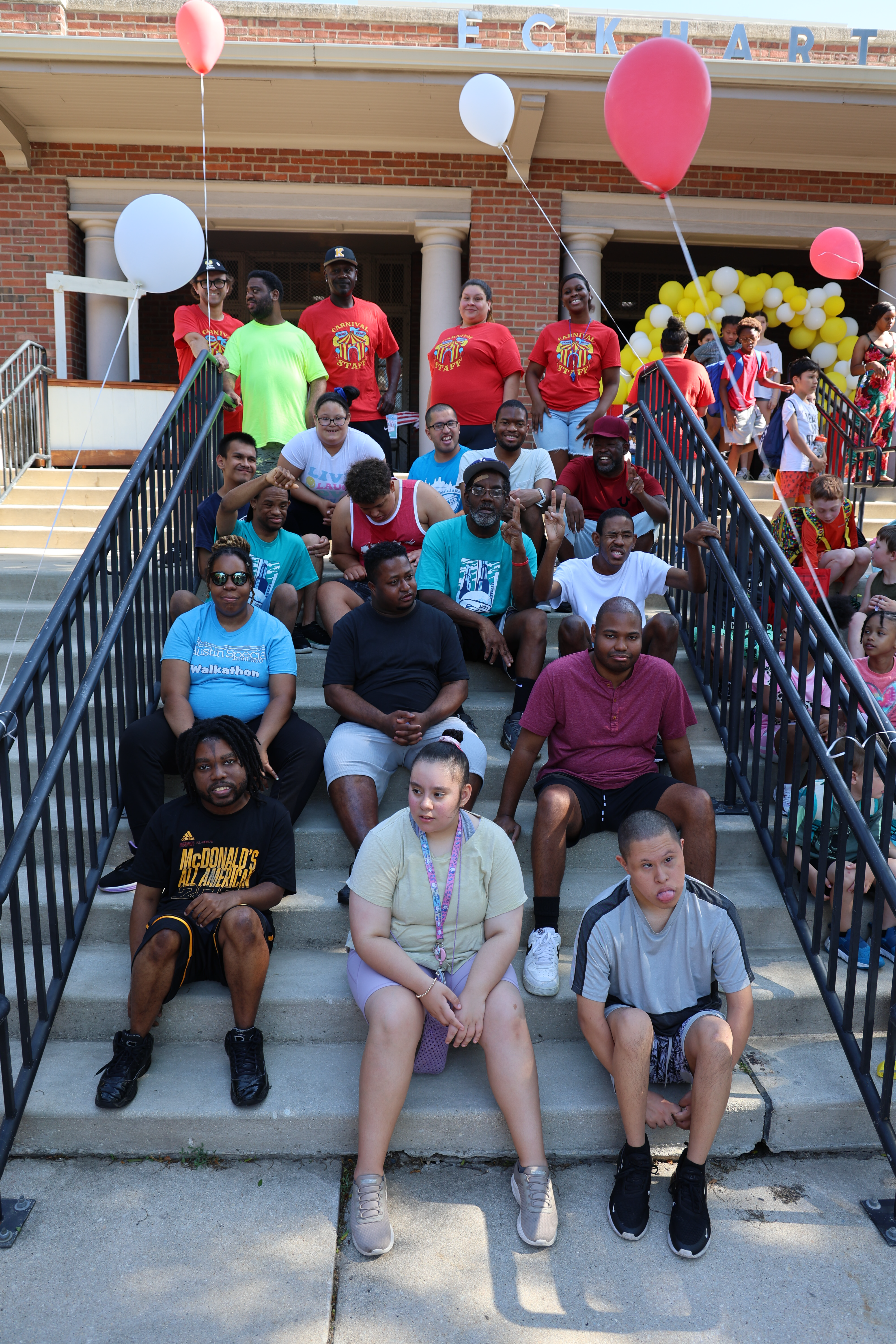 A group of people sit and stand on the steps of Eckhart Park building.