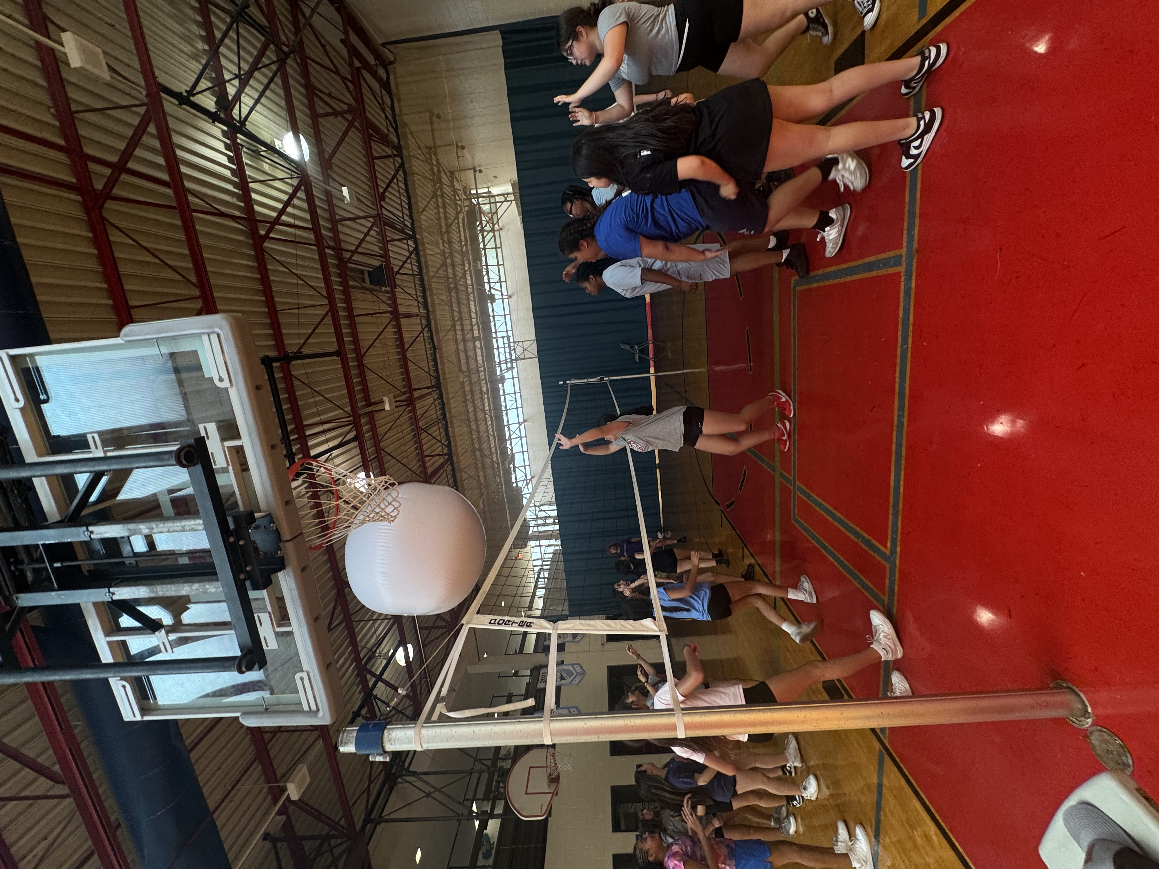 Girls playing volleyball in a gym.