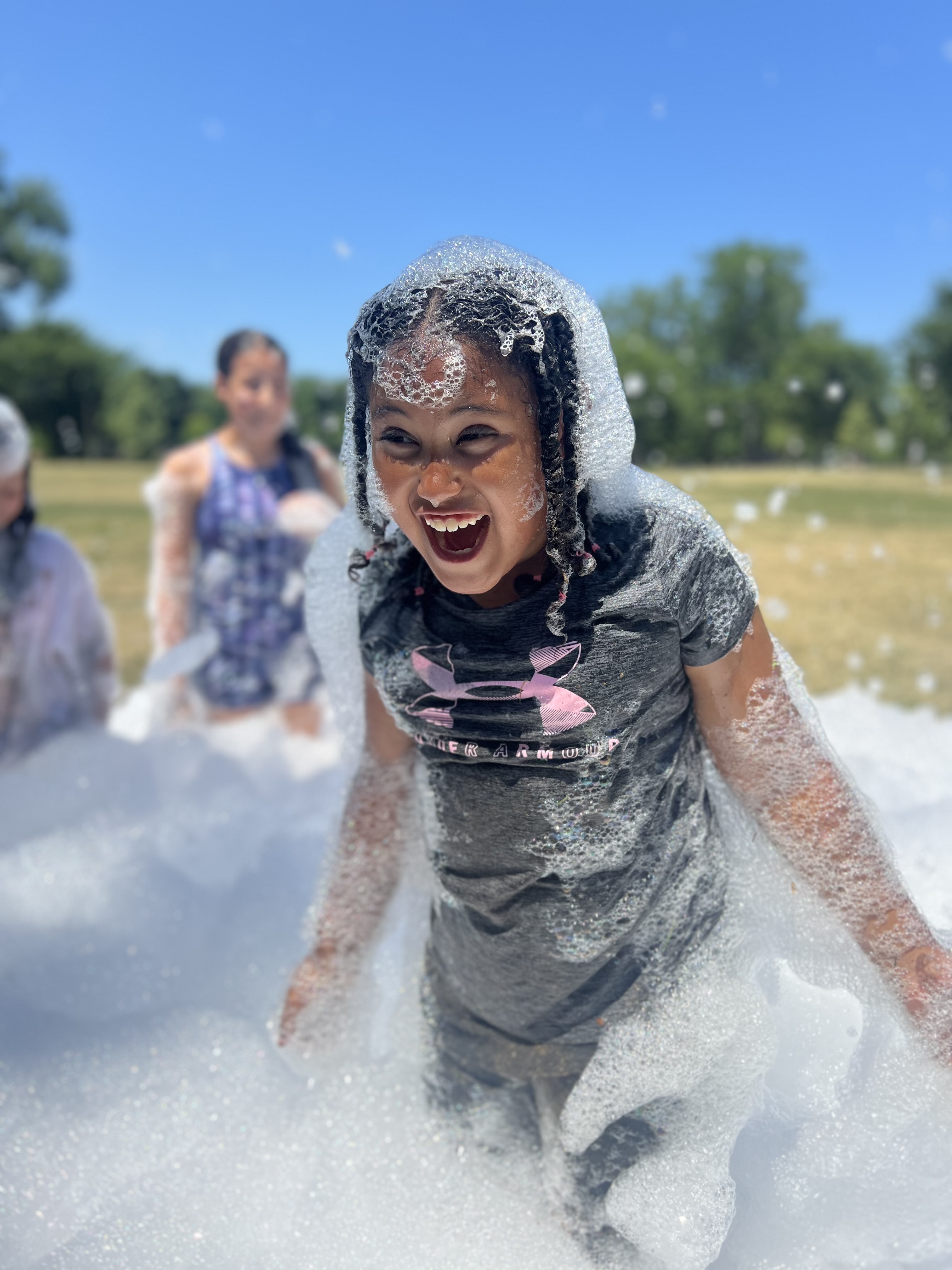 A laughing girl covered in soap suds at a foam party.