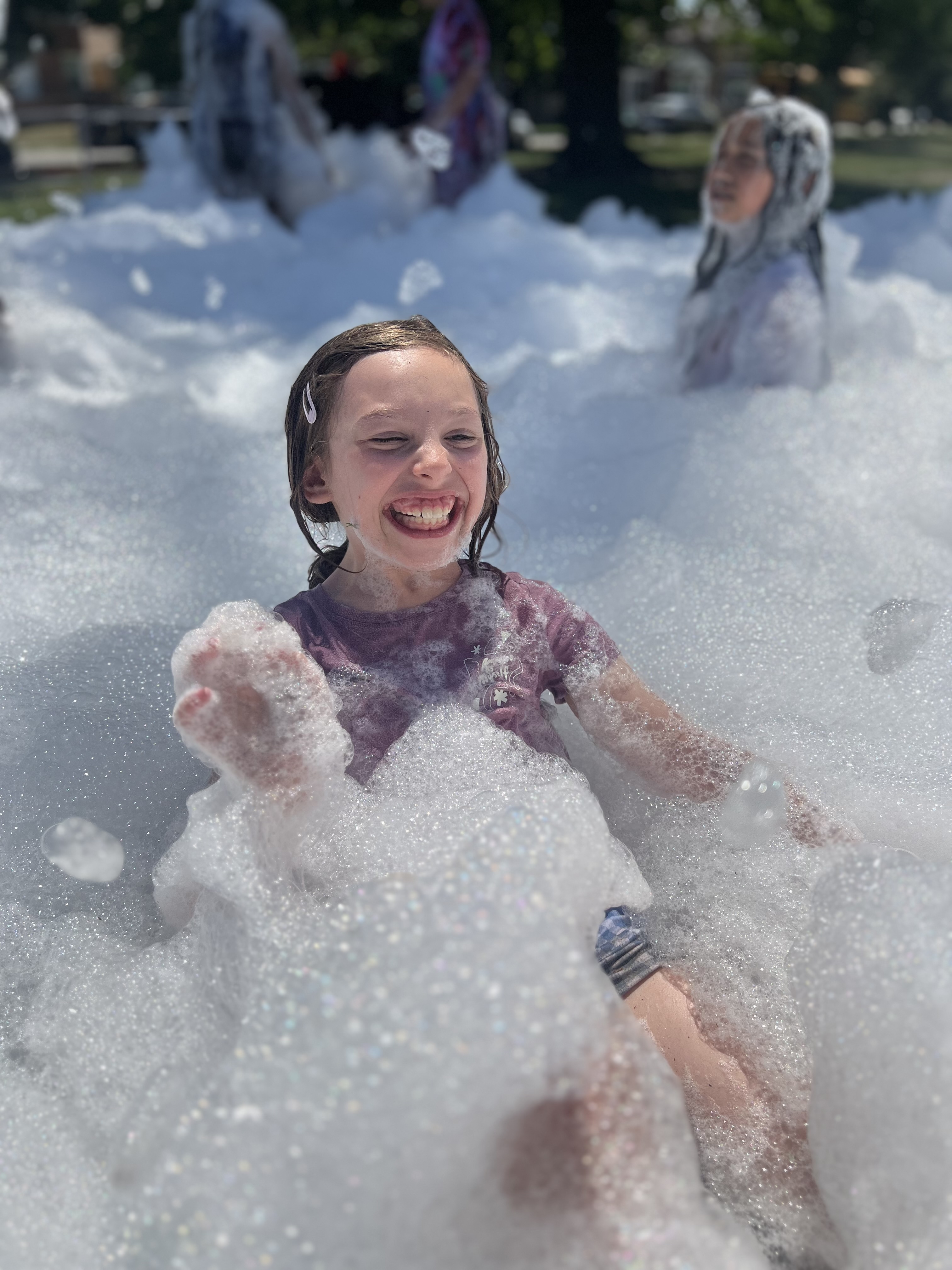Smiling girl playing in a mountain of foam.