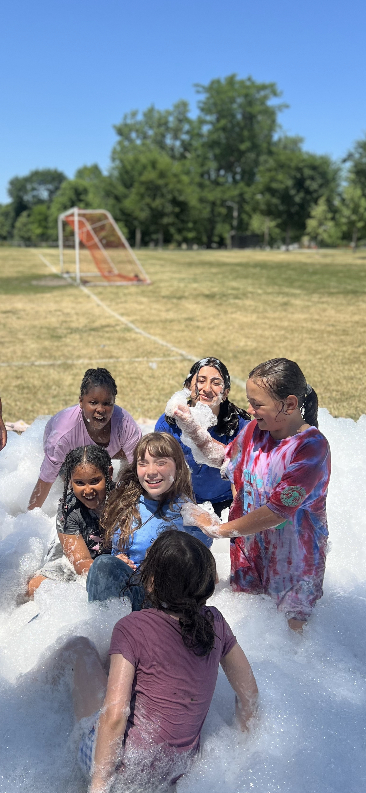 Kids playing in a foam pit on a sunny day.