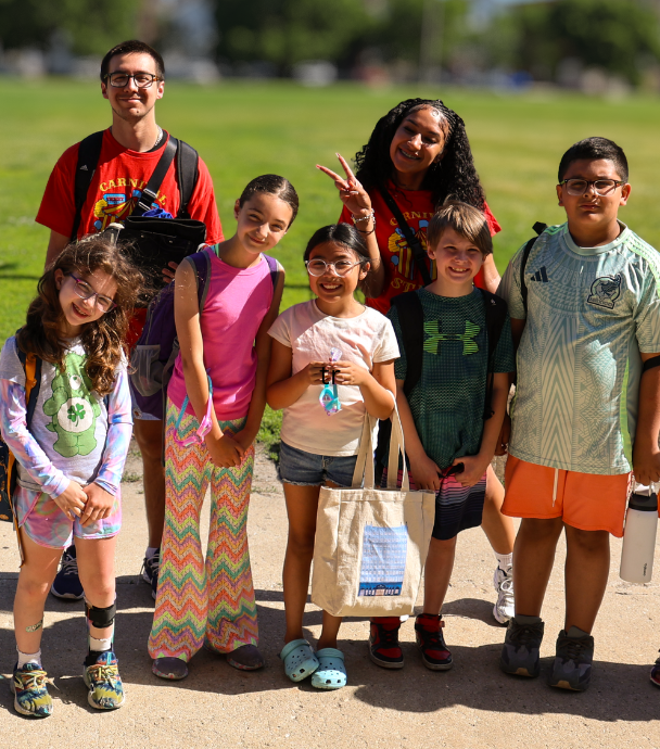 Group of children and teenagers pose for a photo outdoors.