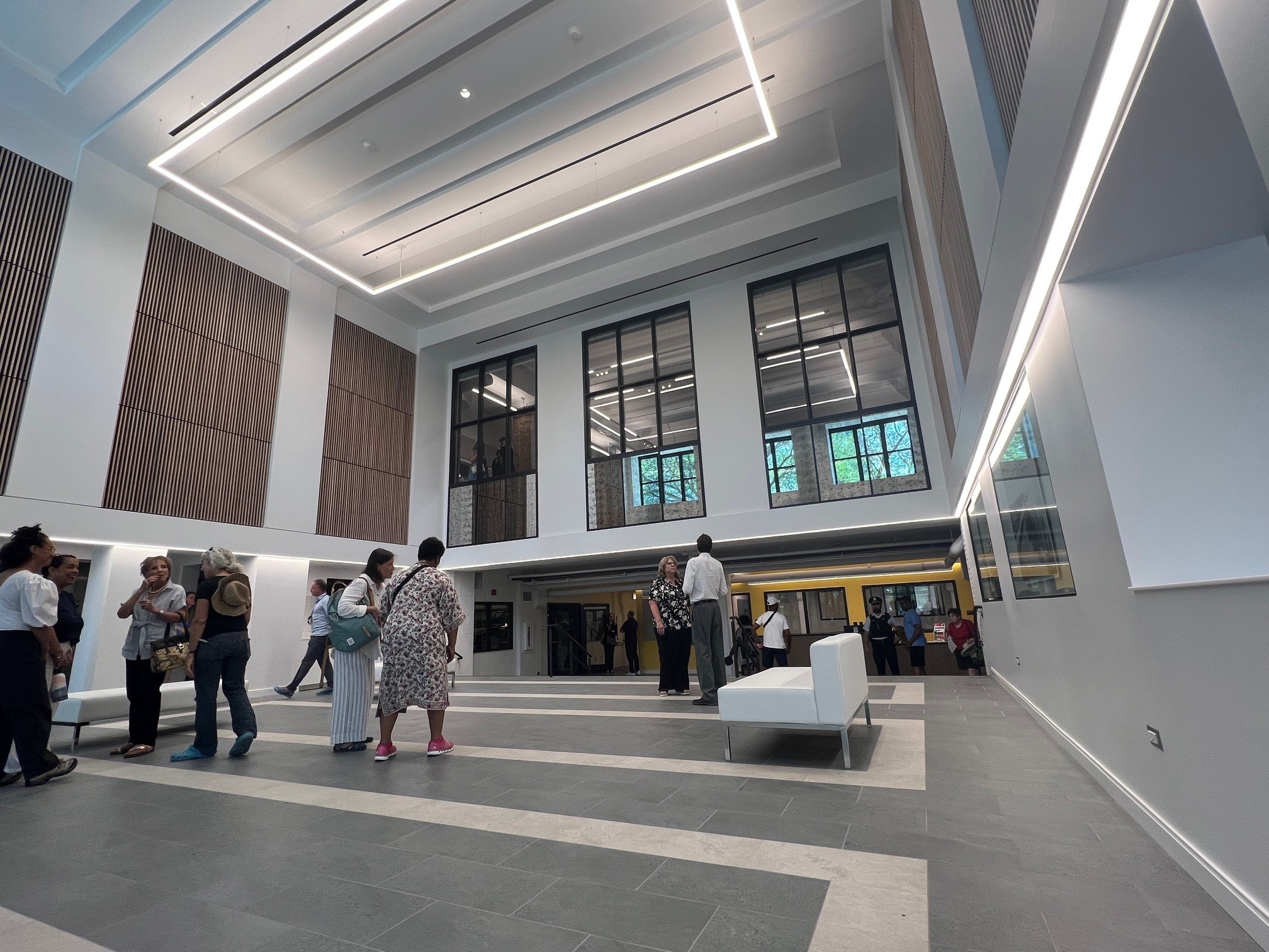 People gather in a spacious, modern atrium with high ceilings and large windows.