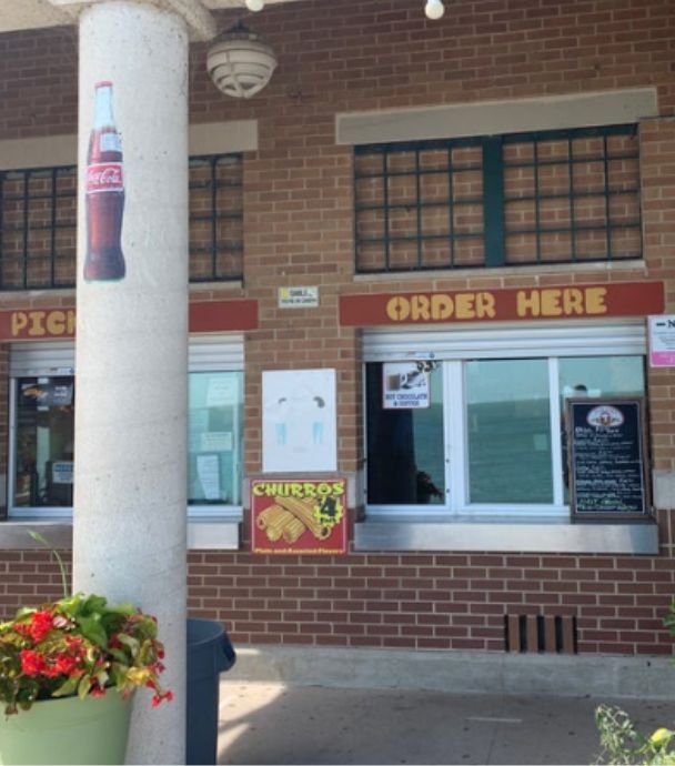 Brick building with an "Order Here" window and a Coca-Cola advertisement on a stone pillar.