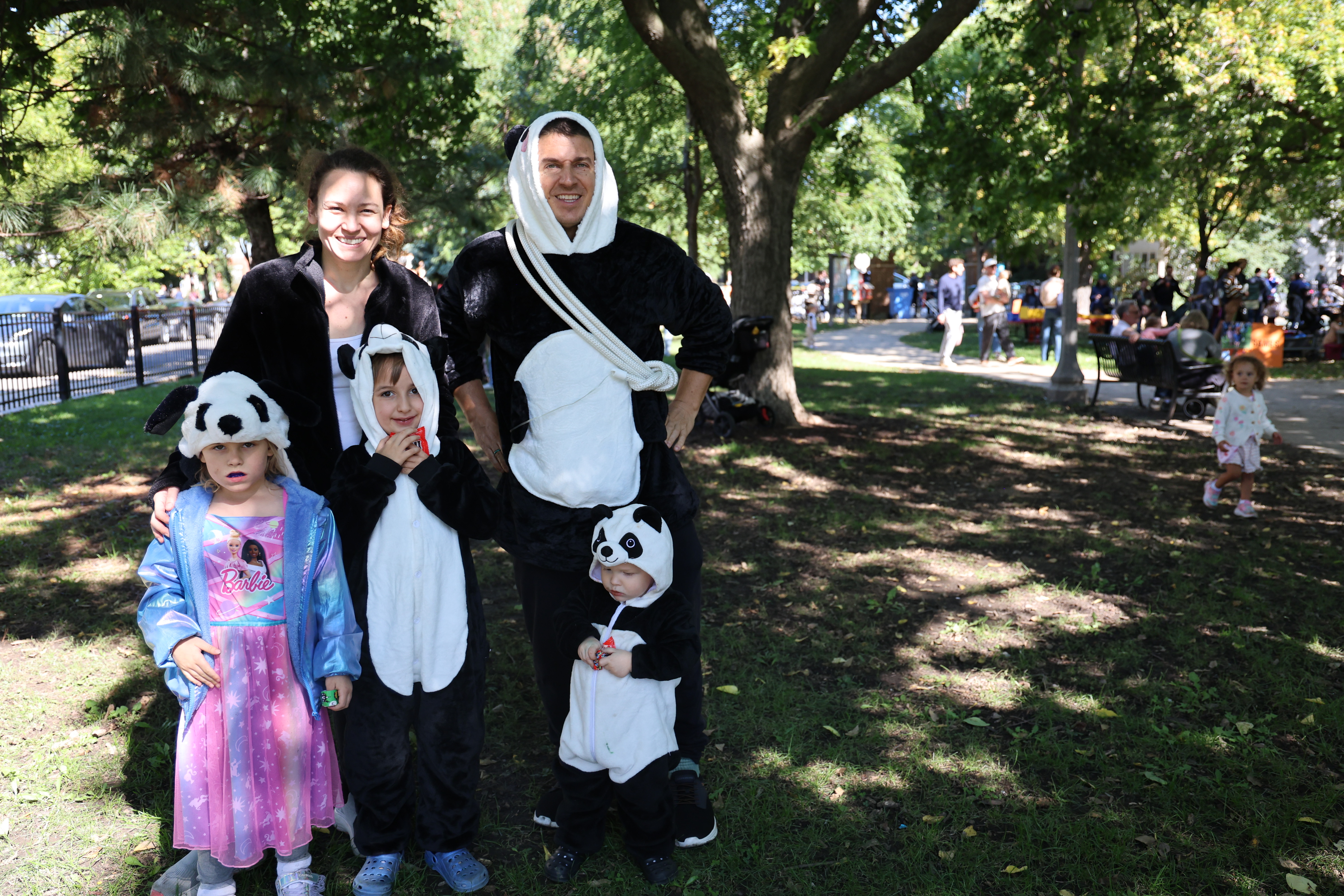 A family in a park wearing panda-themed costumes and hats.
