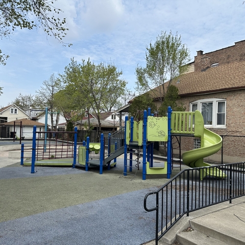 Green and blue playground on a partly-cloudy day.